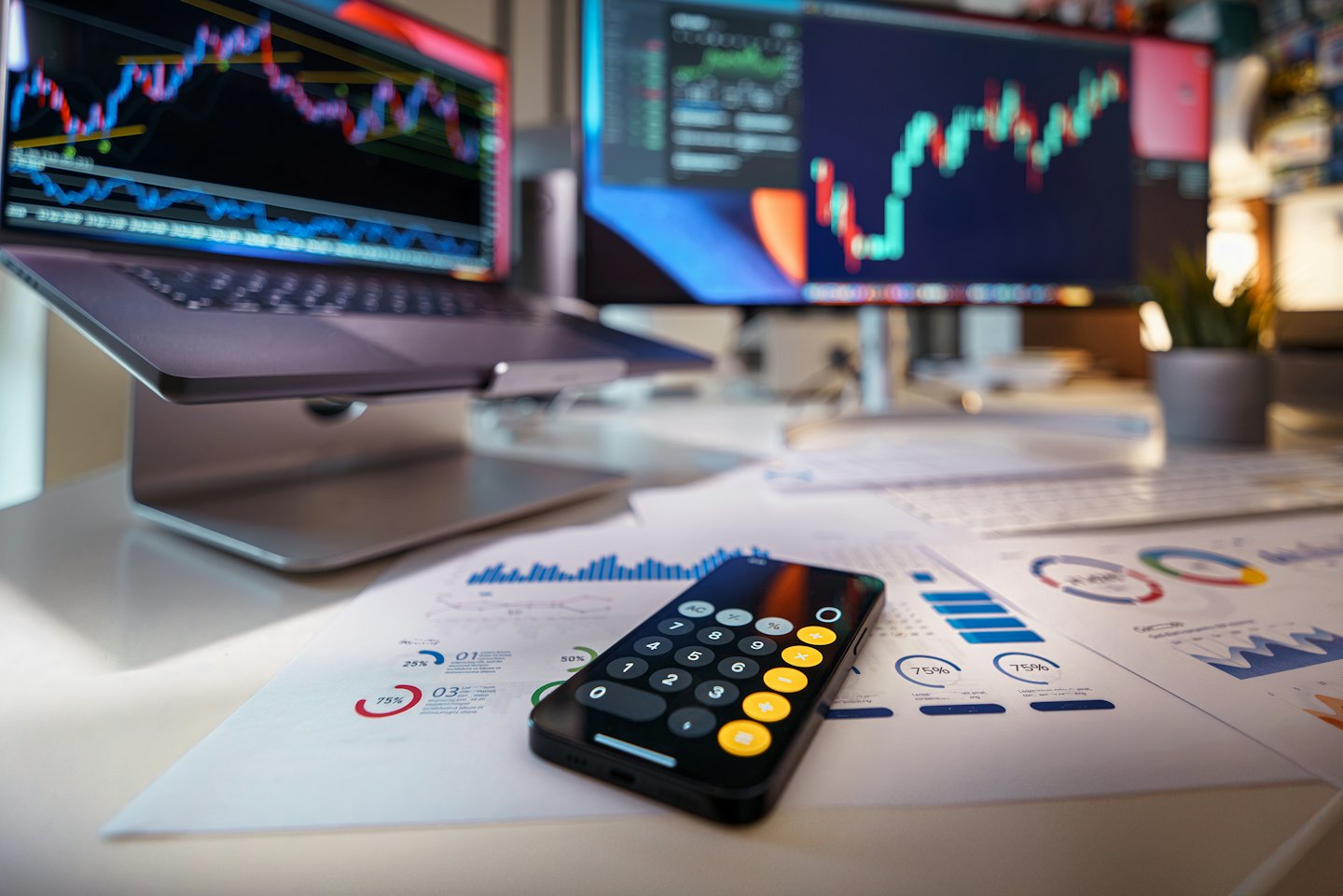 Laptop and smartphone on a desk displaying financial charts and data.