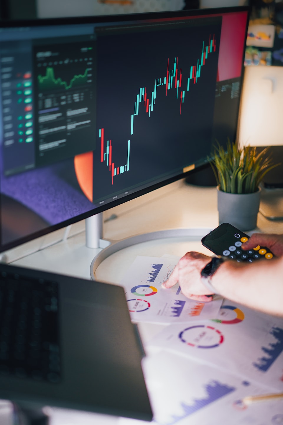 Person analyzes financial data charts on a white desk.